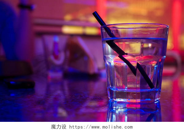 多彩灯光背景中的一杯装满水的玻璃杯